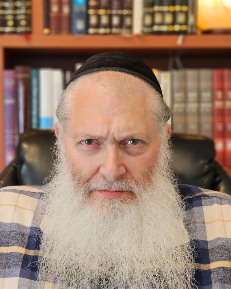 Mordechai Sones in his study, in front of shelves of seforim.